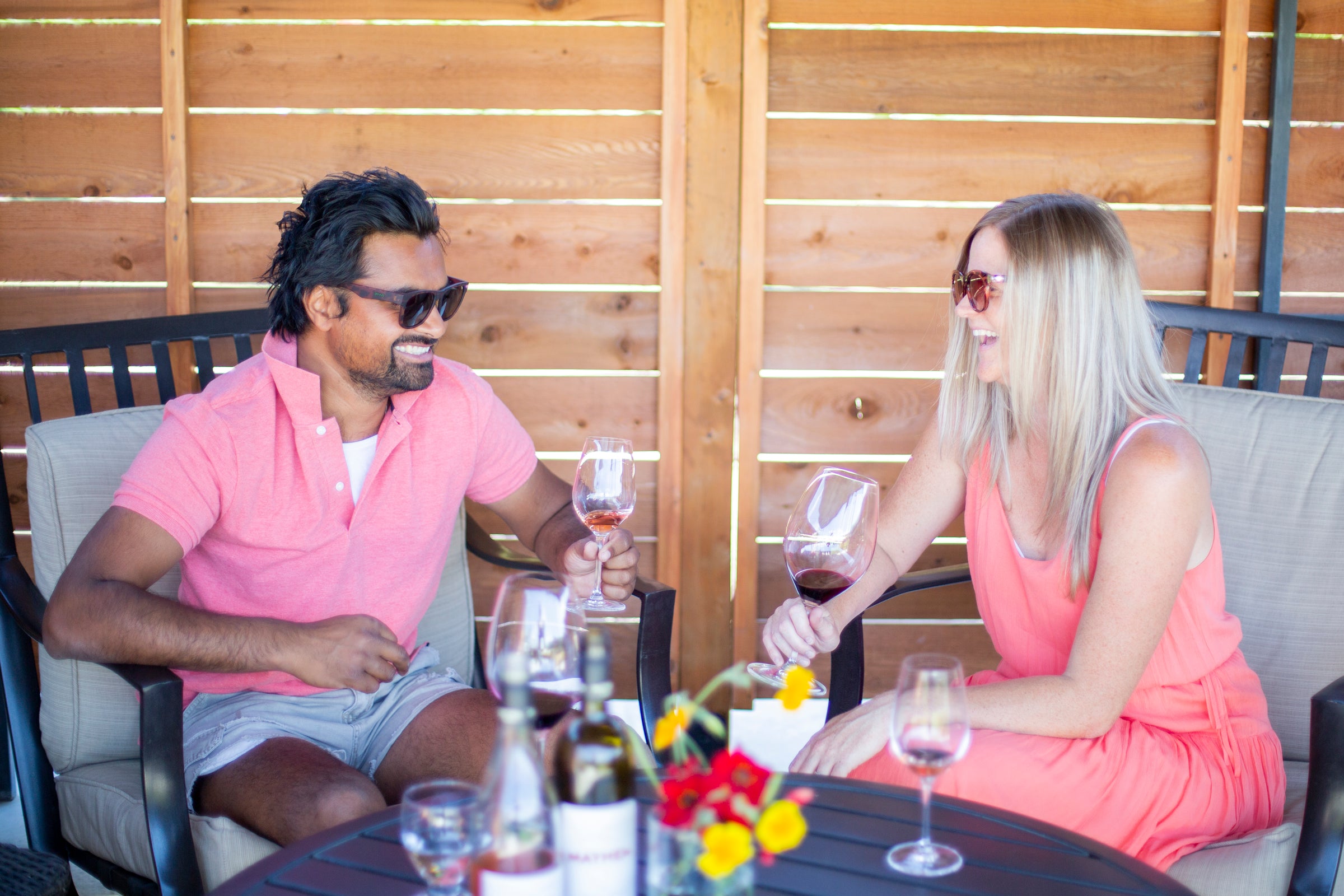 Two people enjoying Mayhem wine on the patio outside